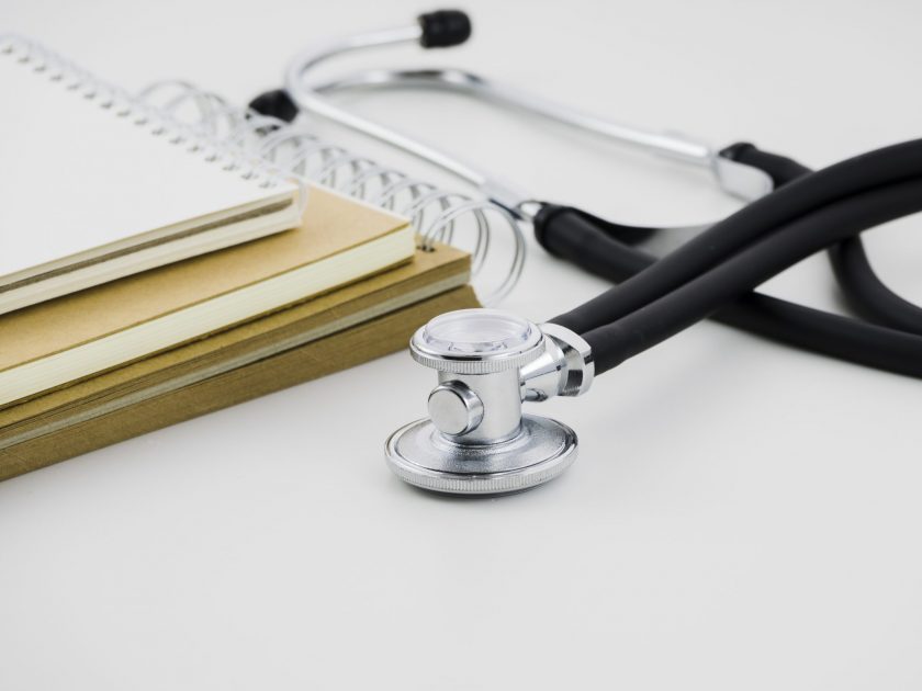 stack-spiral-notepad-stethoscope-white-backdrop
